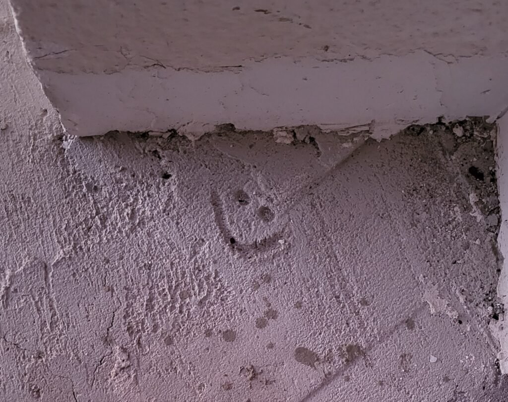 tranquilidad-inversion-inmobiliaria-alicante-estudio-jose-herrera Dibujo de cara sonriente en hormigón que simboliza la tranquilidad de una compra inmobiliaria segura en Alicante con asesoría técnica profesional