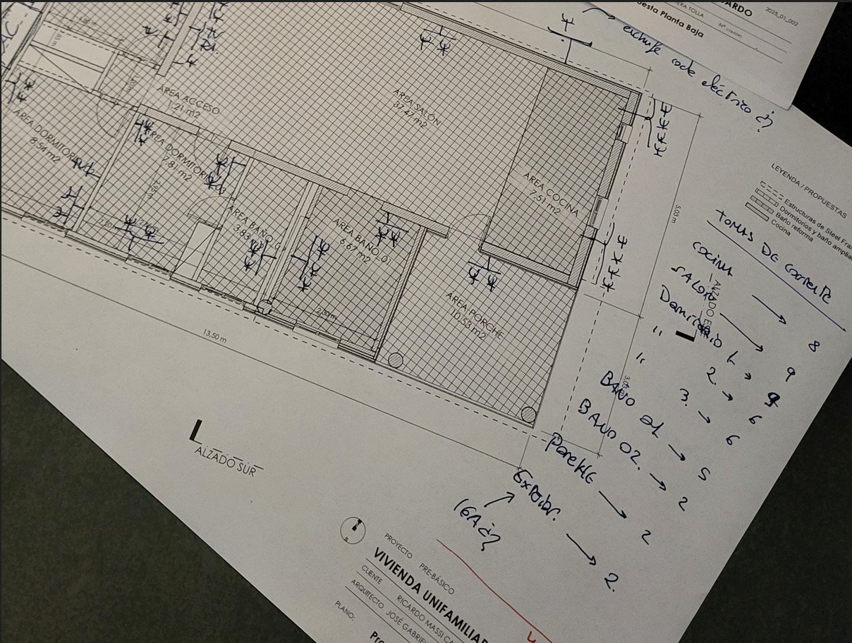 Planos técnicos de un proyecto de arquitectura con anotaciones de estudio sobre una mesa
